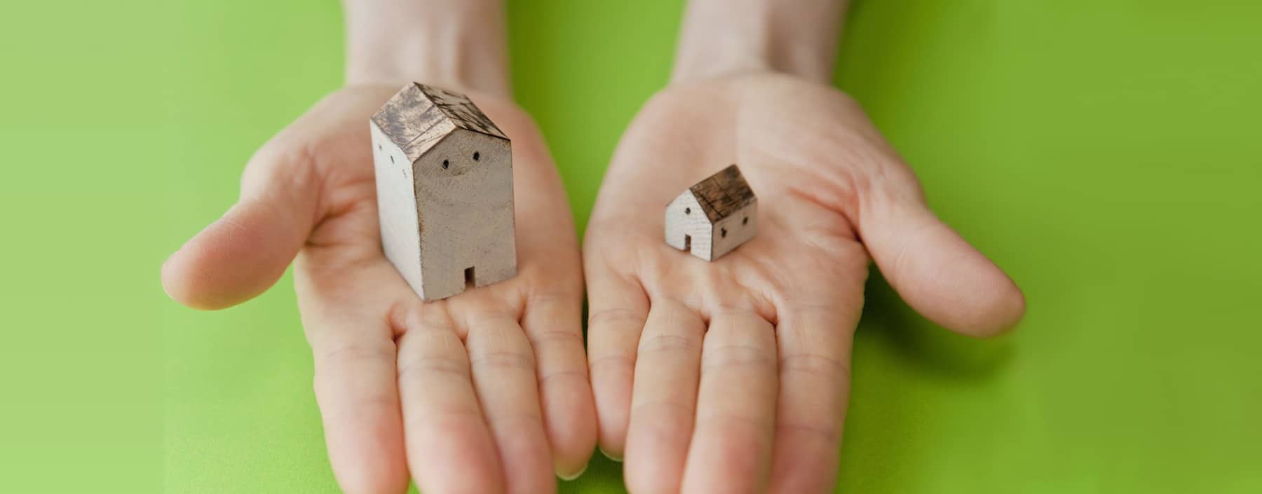 Two model houses held in open hands